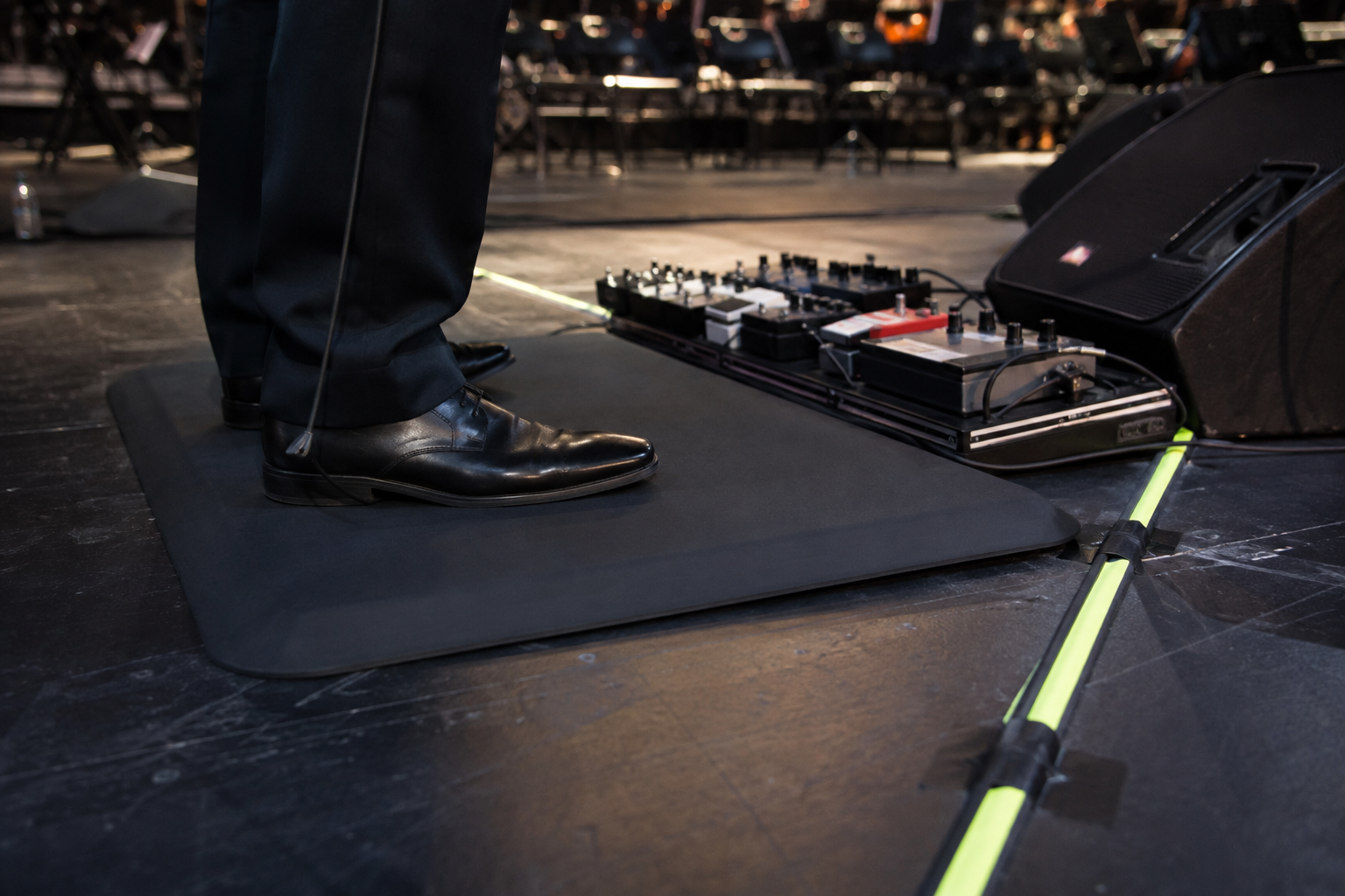 Официални обувки върху скосена anti-fatigue постелка с electric violin pedalboard и маркиран кабелен маршрут отвъд ръба