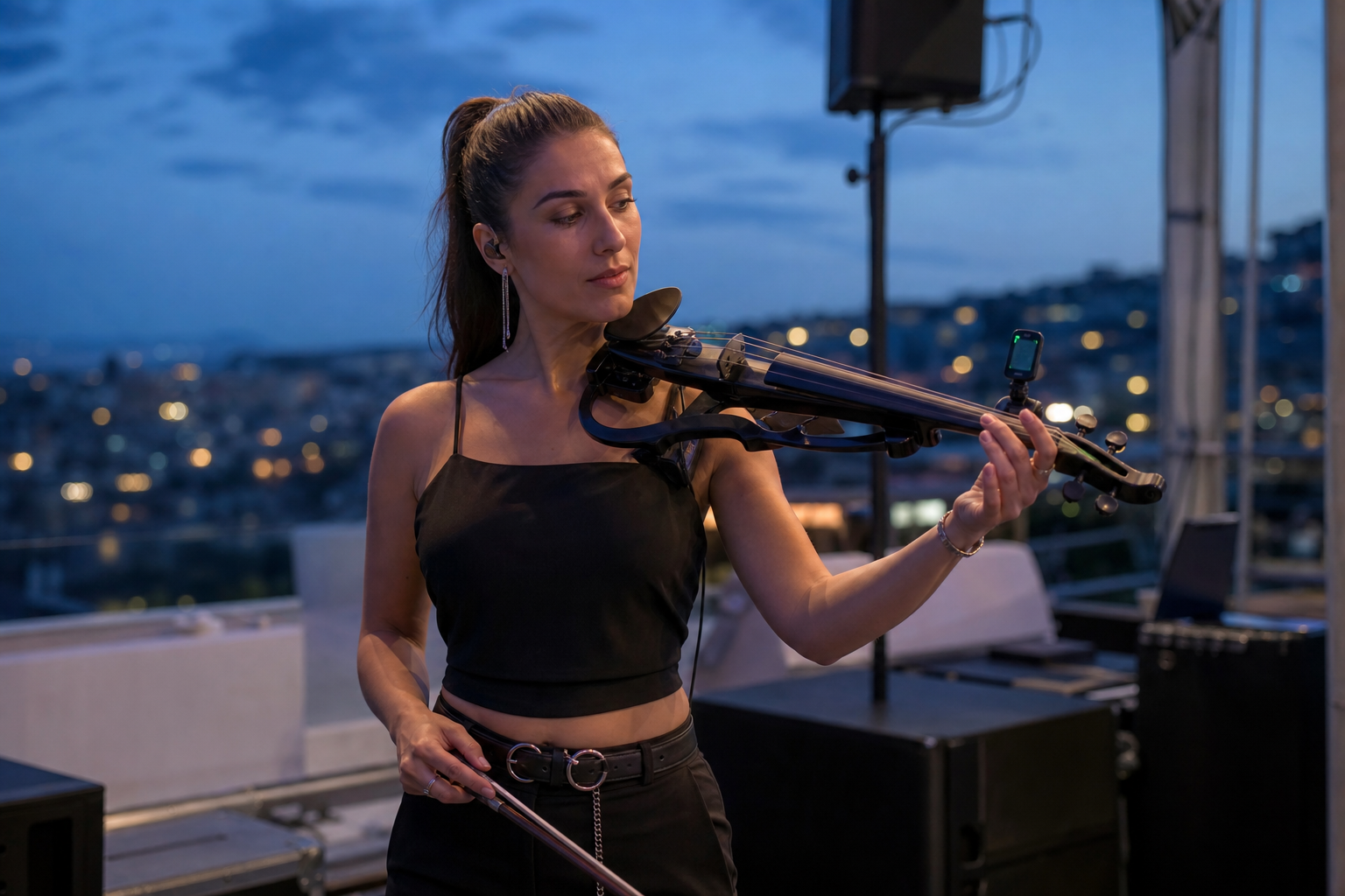 Electric violin изпълнителка проверява clip-on tuner по време на outdoor вечерен soundcheck на покривна или терасовидна сцена
