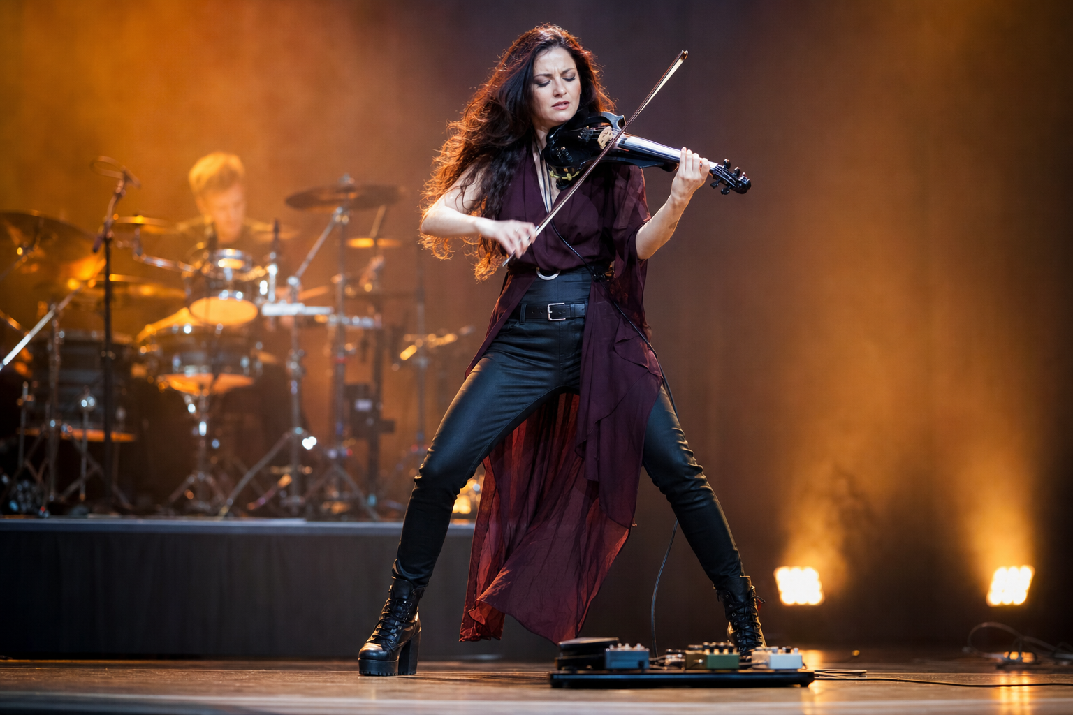 Electric violin изпълнителка в драматичен live момент свири със сатуриран солов тон над малък pedalboard под кехлибарени сценични светлини