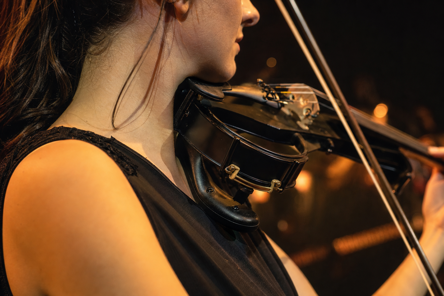 Close-up на electric violin опора за рамо по време на live изпълнение под топли сценични лампи