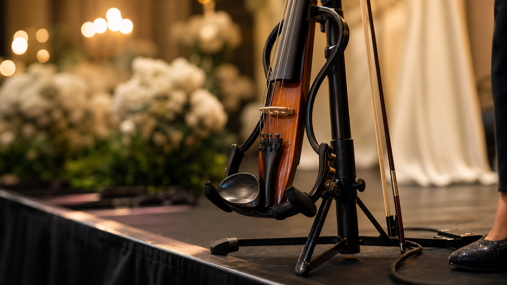 Близък кадър на electric violin, оставен сигурно върху premium черна стойка в края на upscale event сцена по време на бърз performer reset